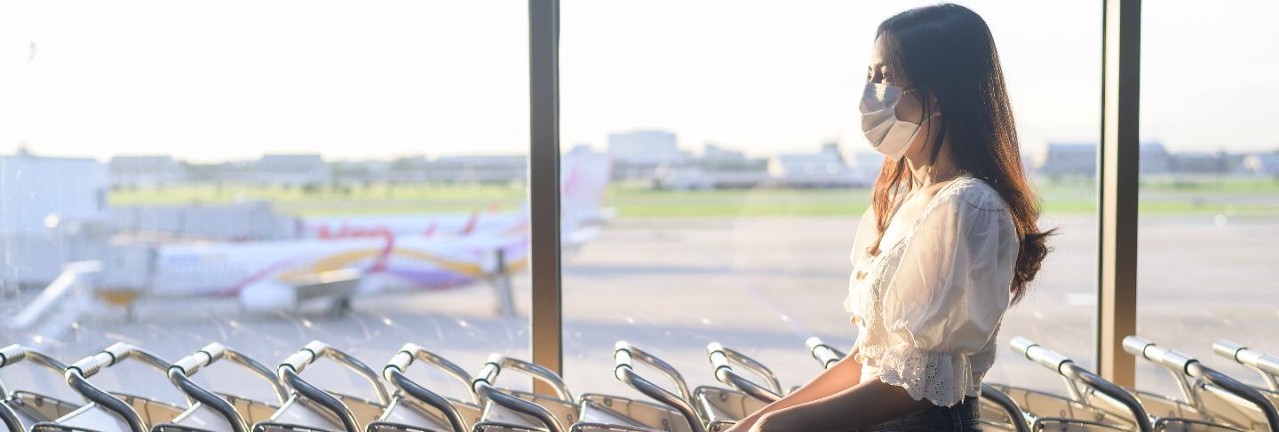 A traveller woman is wearing protective mask in international airport, travel under covid-19 pandemic, safety travels, social distancing protocol
