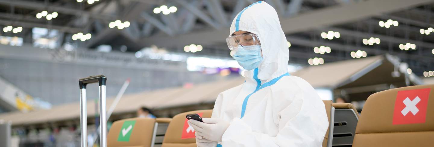 An asian man is wearing ppe suit in international airport , safety travel , covid-19 protection , social distancing concept