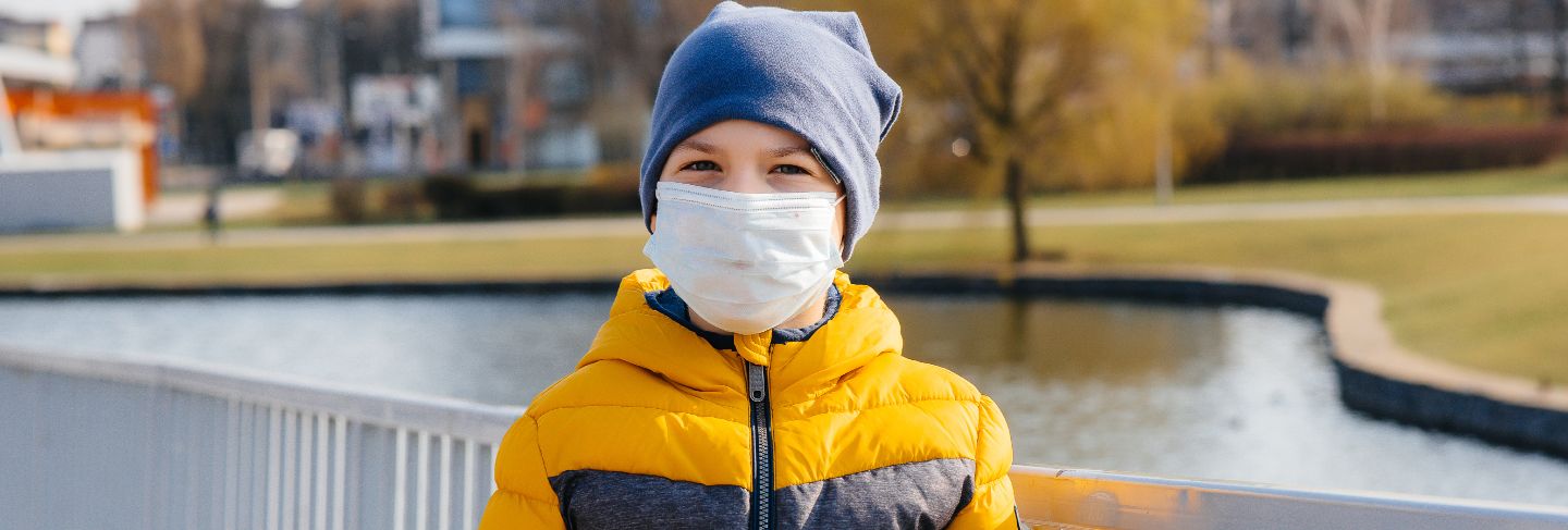 A boy stands on a gray background in a mask during a quarantine with free space. quarantine in the mask.