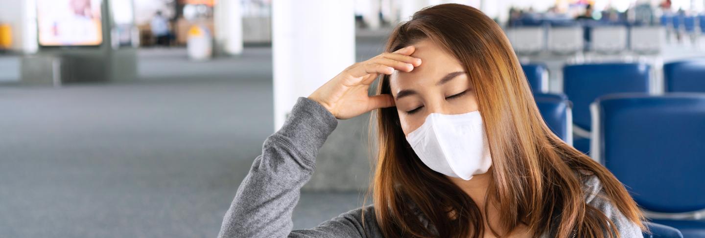 Asian woman with a surgical face mask waiting in the airport