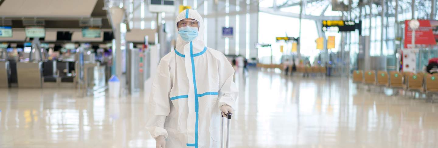 An asian man is wearing ppe suit in international airport , safety travel , covid-19 protection , social distancing concept