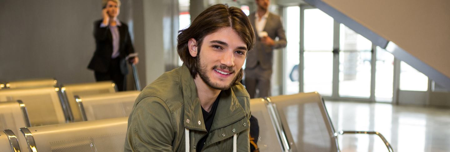 Man with passport and boarding pass sitting in waiting area