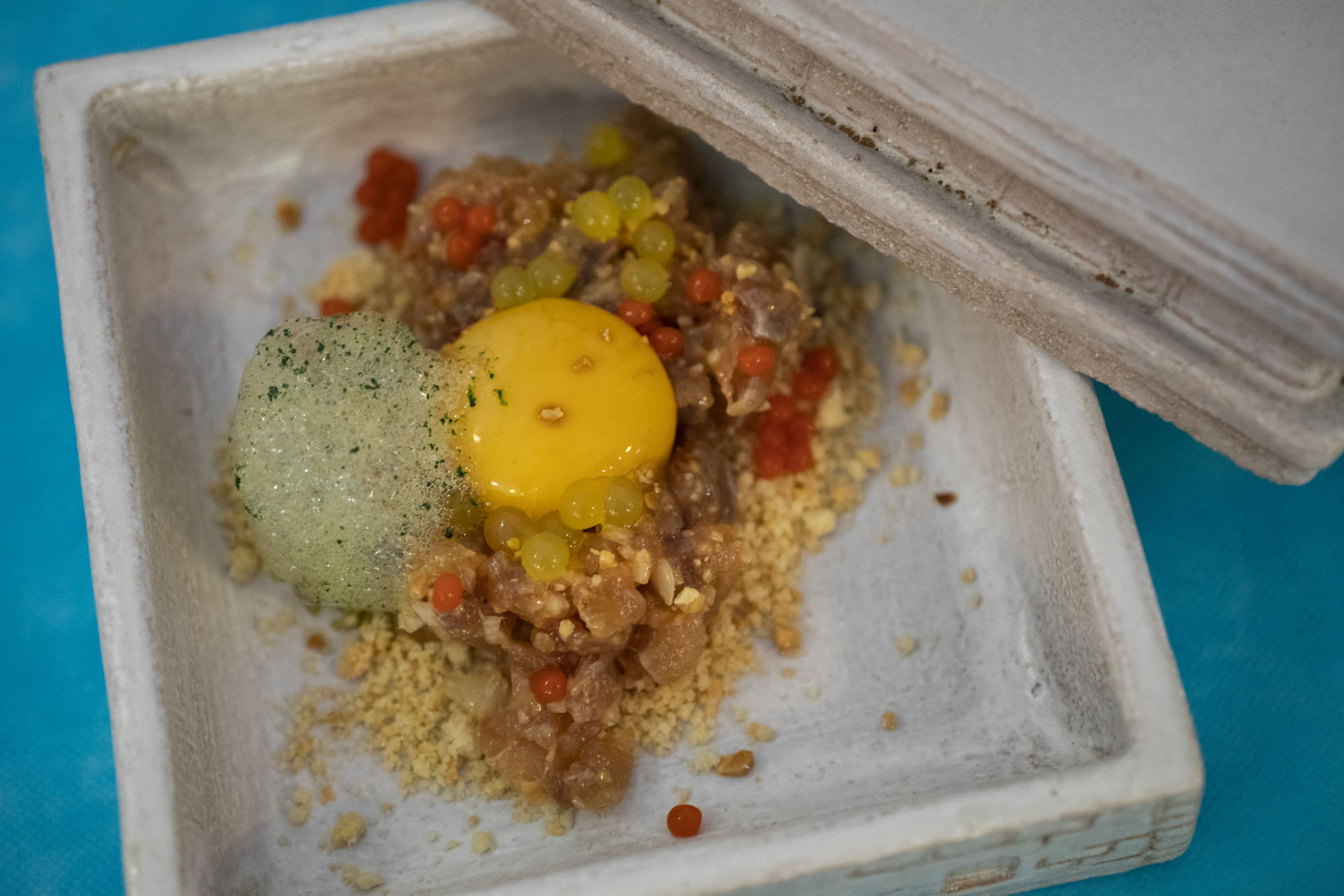 Tartar de ijada de lecha con huevo semi curado en soja, curry verde, apio, cítricos, perlas de tomate, crumble de almendra y aceite de carbón. Tartar de ijada de lecha con huevo semi curado en soja, curry verde, apio, cítricos, perlas de tomate, crumble de almendra y aceite de carbón.
