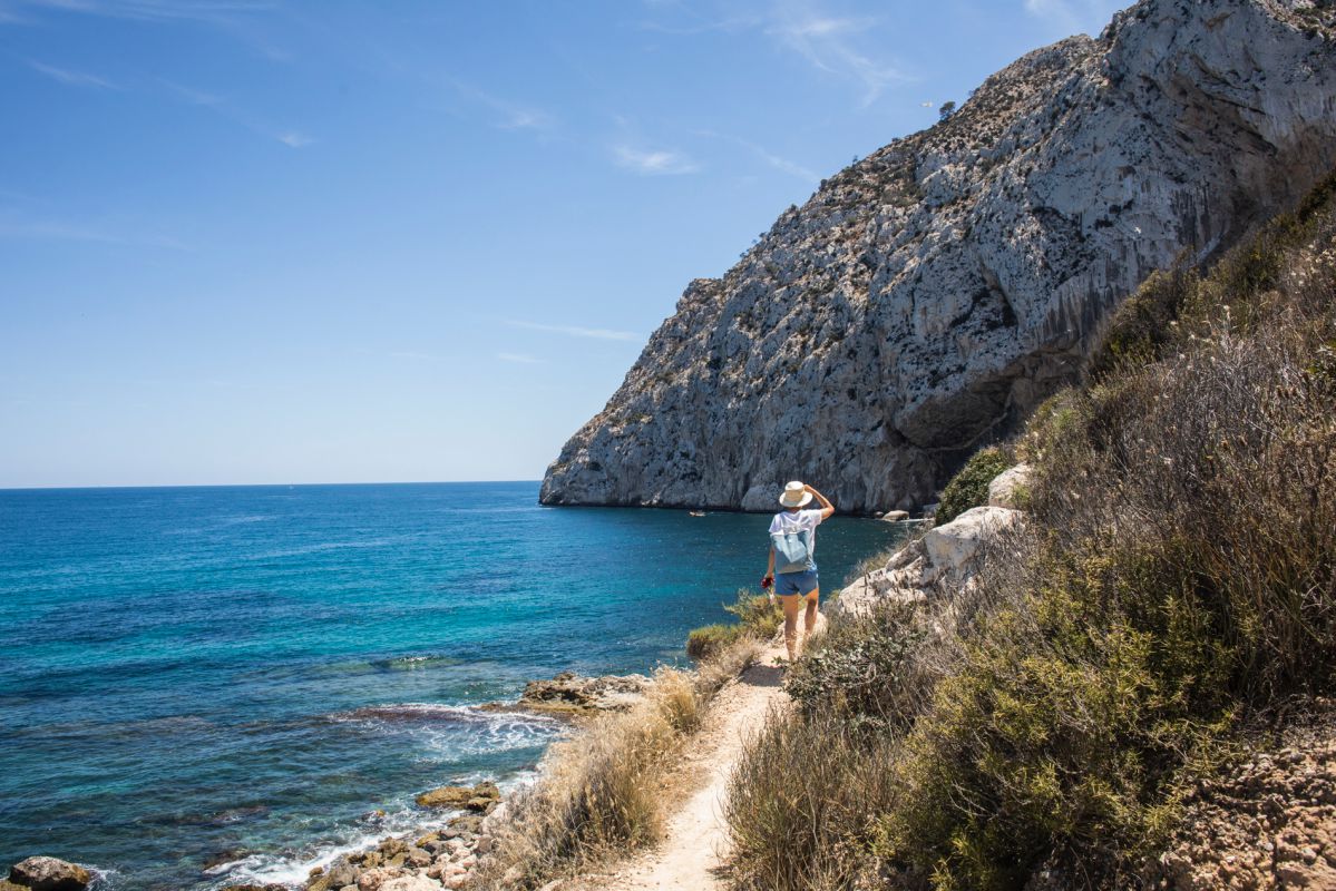 Una turista camina con su perro por el sendero que lleva hacia la cala del Peñón de Ifach, en Calpe, Alicante. Una turista camina con su perro por el sendero que lleva hacia la cala del Peñón de Ifach, en Calpe, Alicante.