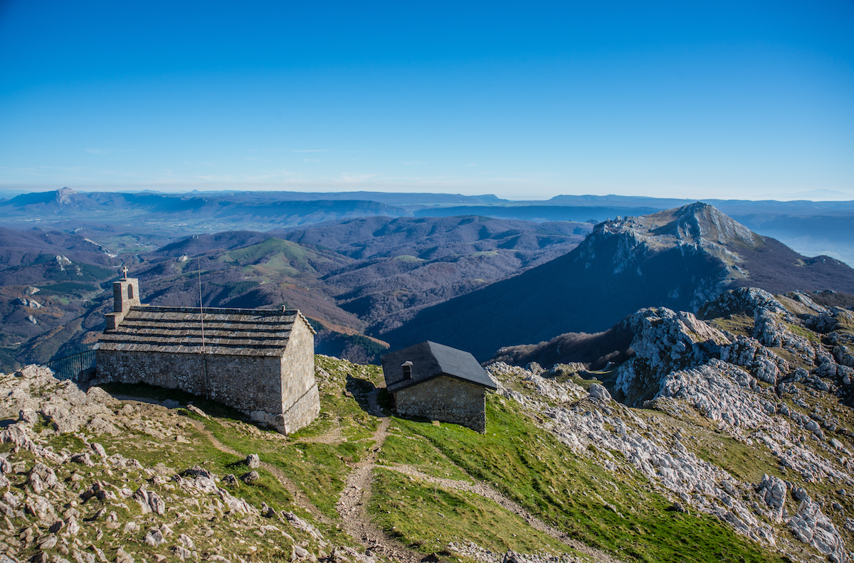 Vistas de la ermita del Santo Cristo y del refugio desde la cima del Aizkorri. Foto: Shutterstock. Vistas de la ermita del Santo Cristo y del refugio desde la cima del Aizkorri. Foto: Shutterstock.