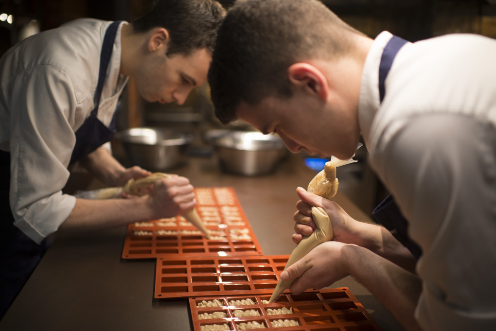 Dos cocineros rellenan unos moldes Dos cocineros rellenan unos moldes