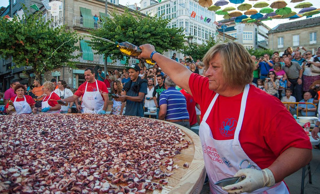 Mujer echando aceite sobre gran cantidad de pulpo Mujer echando aceite sobre gran cantidad de pulpo