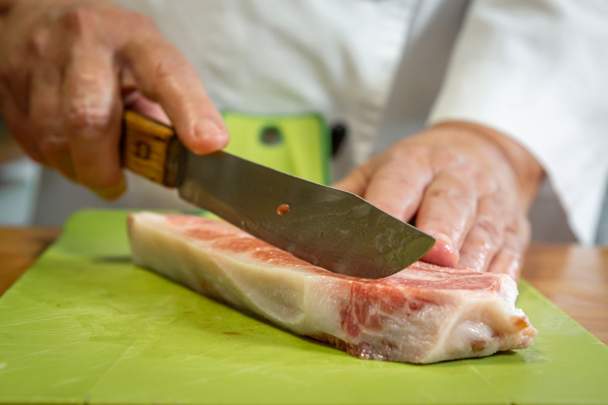 Cortando con un afilado cuchillo un fliete de atún crudo en dados para la receta del poke bowl de atún picante. Cortando con un afilado cuchillo un fliete de atún crudo en dados para la receta del poke bowl de atún picante.