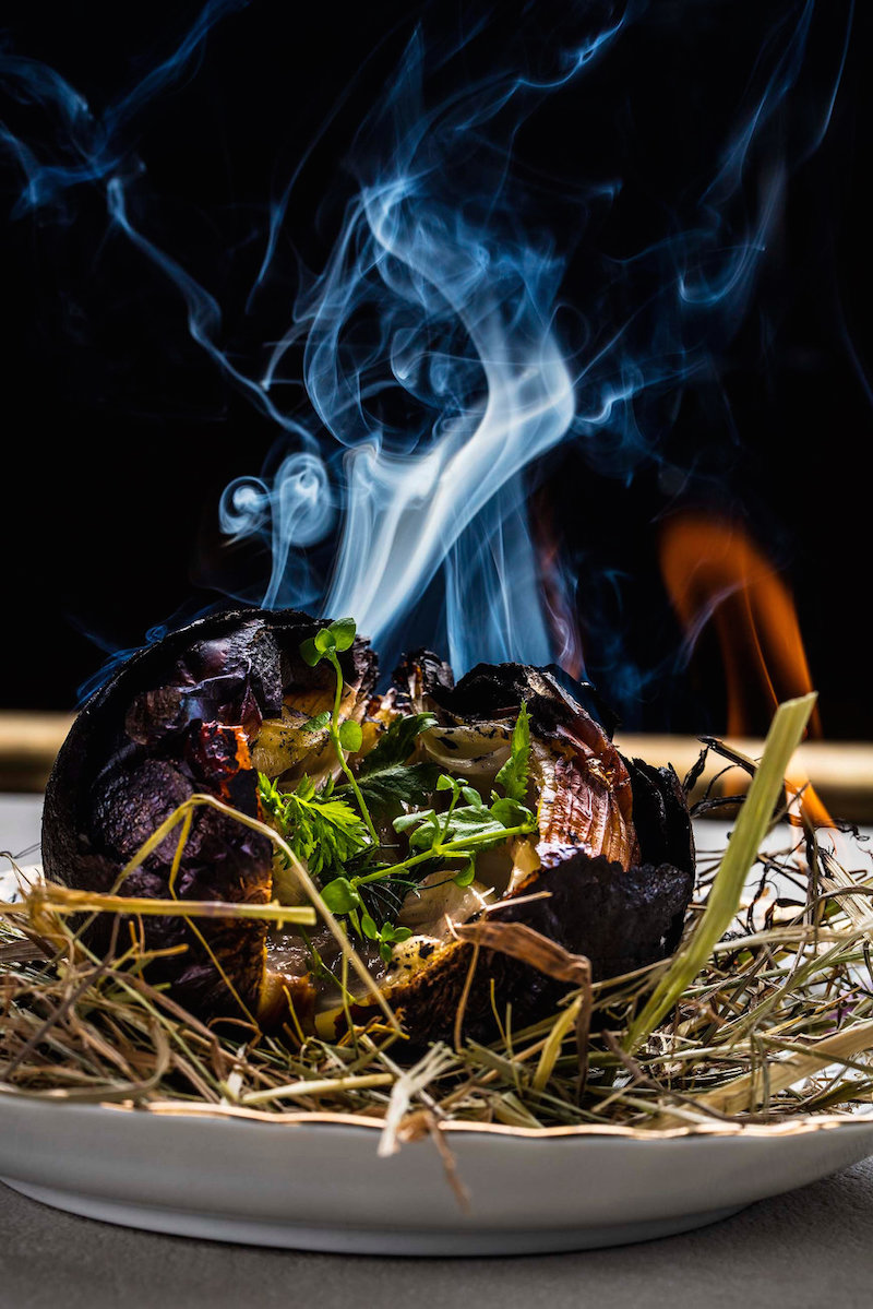 La cebolla negra, hecha a la brasa como los calçots y aliñada con garum casero y hierbas aromáticas. La cebolla negra, hecha a la brasa como los calçots y aliñada con garum casero y hierbas aromáticas.