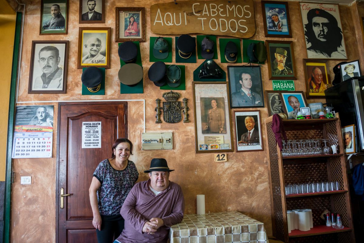 El matrimonio propietario del guachinche Bodega El Zacatín, Eladio y Nina, en Tenerife, posando junto a la pared donde cuelgan fotos de los más dispares dirigentes políticos. El matrimonio propietario del guachinche Bodega El Zacatín, Eladio y Nina, en Tenerife, posando junto a la pared donde cuelgan fotos de los más dispares dirigentes políticos.