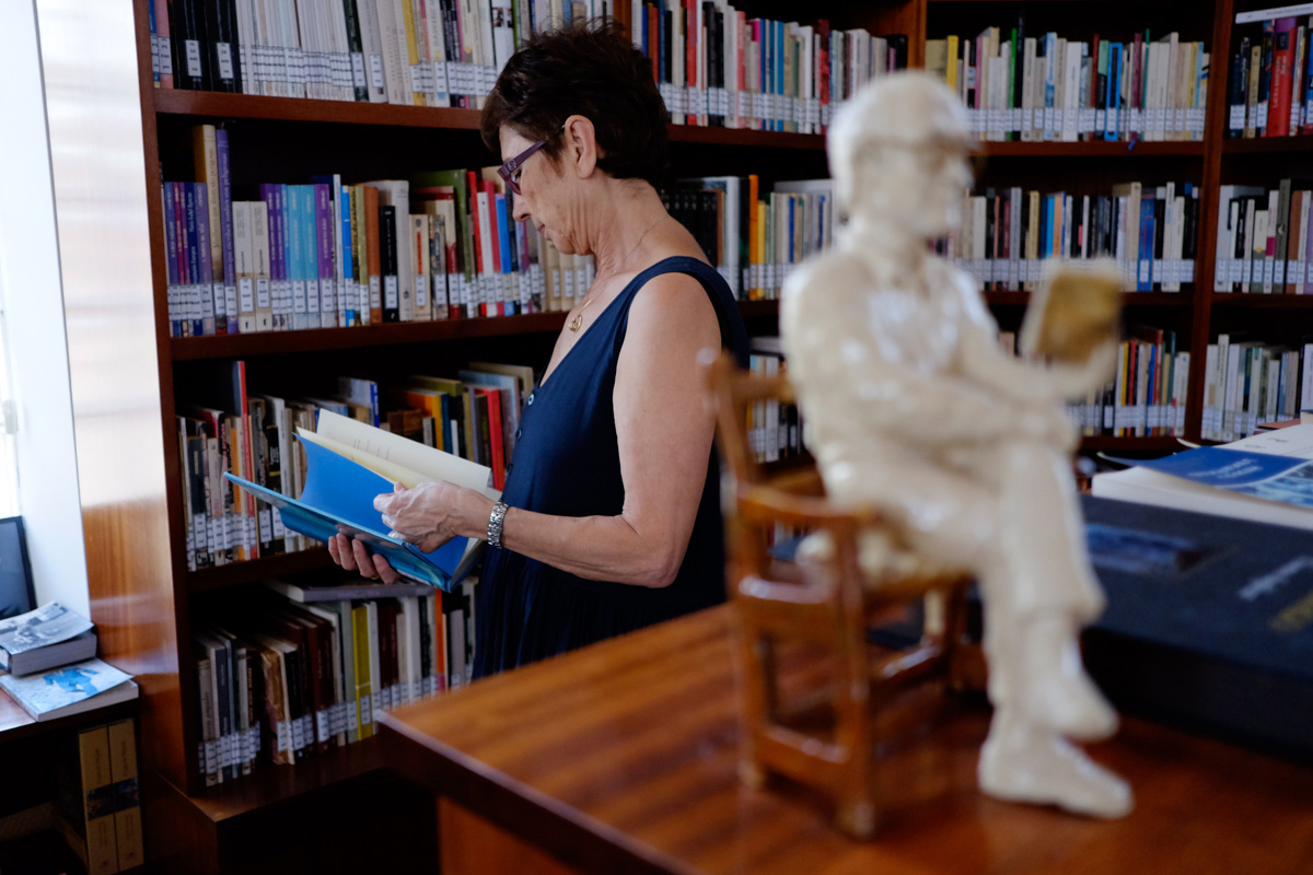 Pilar del Río con un libro en las manos y con la escultura del escritor leyendo en un primer plano. Pilar del Río con un libro en las manos y con la escultura del escritor leyendo en un primer plano.