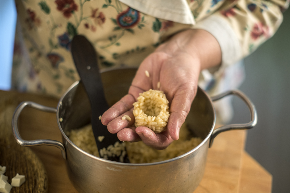 Cuando el arroz se puede colocar en la palma de la mano sin quemarse, hacer una bola más o menos como un huevo grande. Cuando el arroz se puede colocar en la palma de la mano sin quemarse, hacer una bola más o menos como un huevo grande.