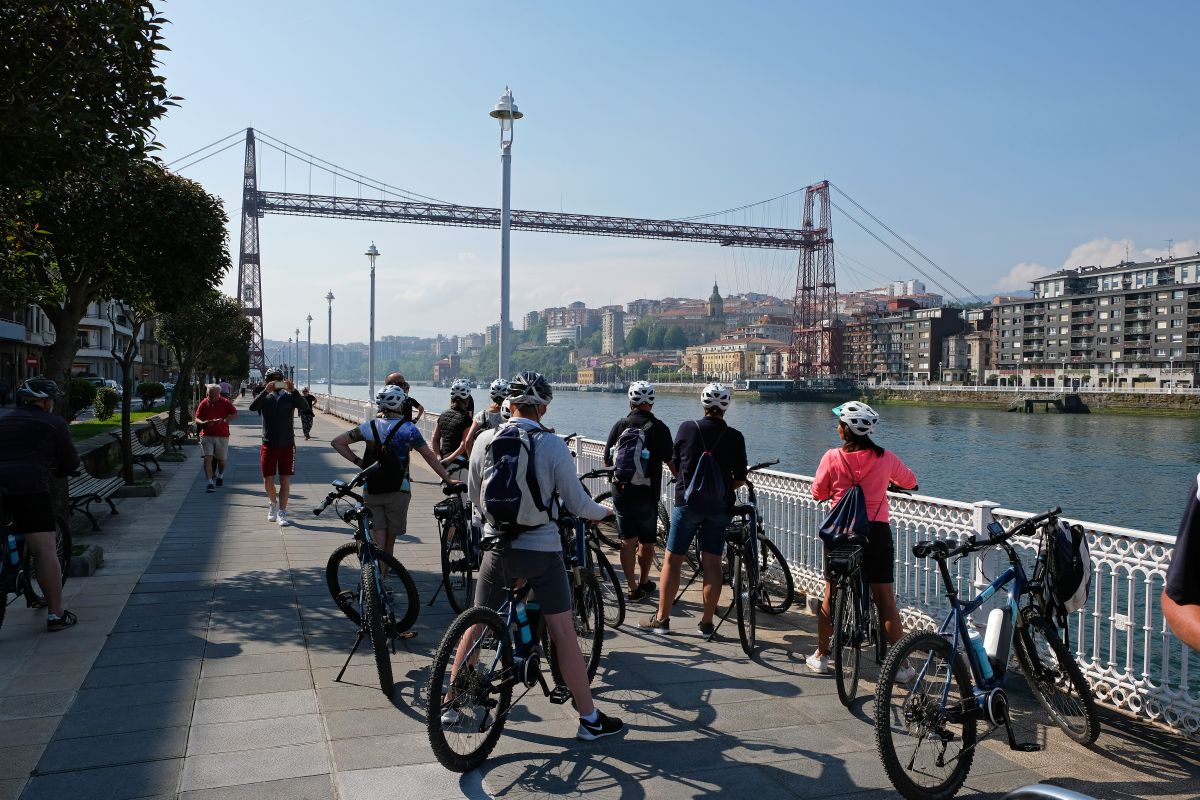 Un grupo de ciclistas observan el Puente Colgante cerca del monumento a Evaristo Churruca, en Getxo (Vizcaya). Un grupo de ciclistas observan el Puente Colgante cerca del monumento a Evaristo Churruca, en Getxo (Vizcaya).