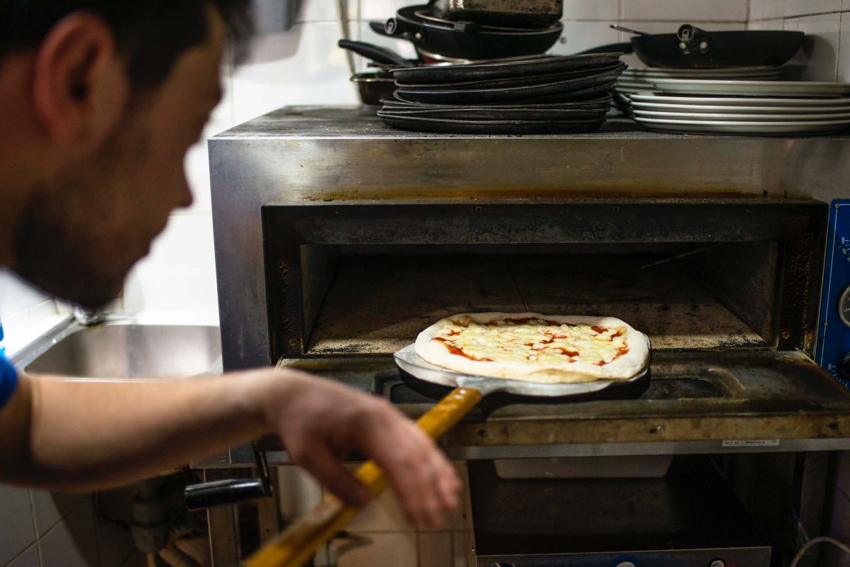 Mikele Corsalini metiendo la pizza margarita en el horno de 'La pizza è bella', en Madrid. Mikele Corsalini metiendo la pizza margarita en el horno de 'La pizza è bella', en Madrid.