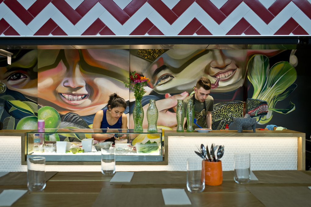 El equipo de Roberto preparando la comanda con el colorido mural que define su cocina al fondo. El equipo de Roberto preparando la comanda con el colorido mural que define su cocina al fondo.