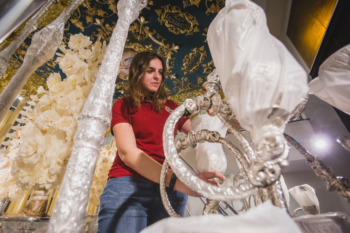 La joven auxiliar de priostía coloca los guardabrisas de los candelabros de cola del palio de la Virgen de Consolación. La joven auxiliar de priostía coloca los guardabrisas de los candelabros de cola del palio de la Virgen de Consolación.