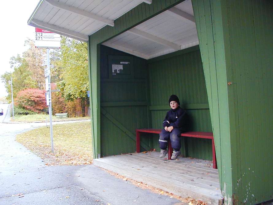 Pojken väntar på bussen.