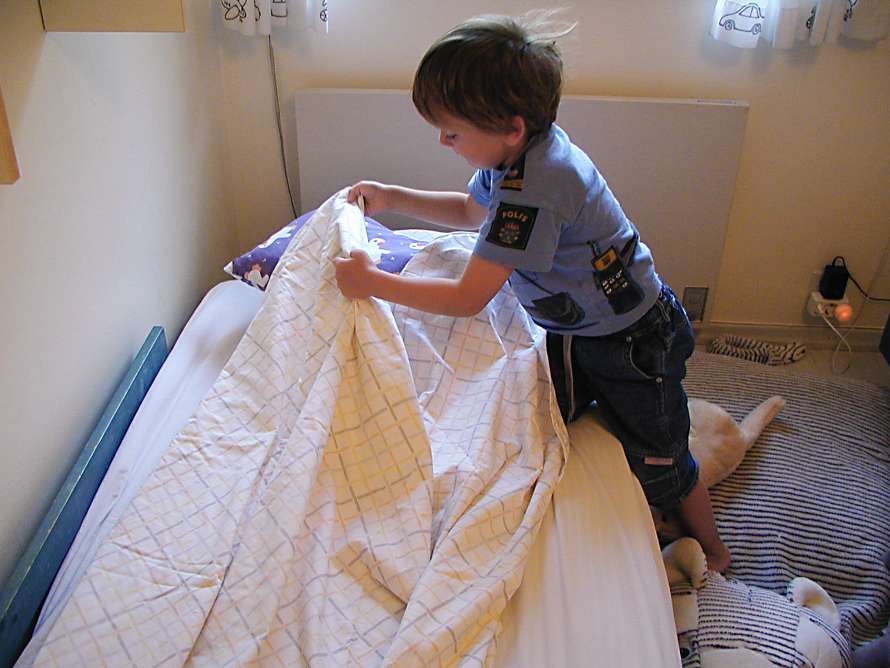 Pojken bäddar sin säng.