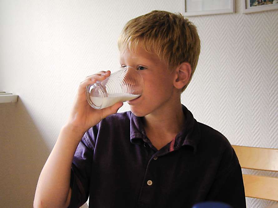 Pojken dricker kall mjölk.