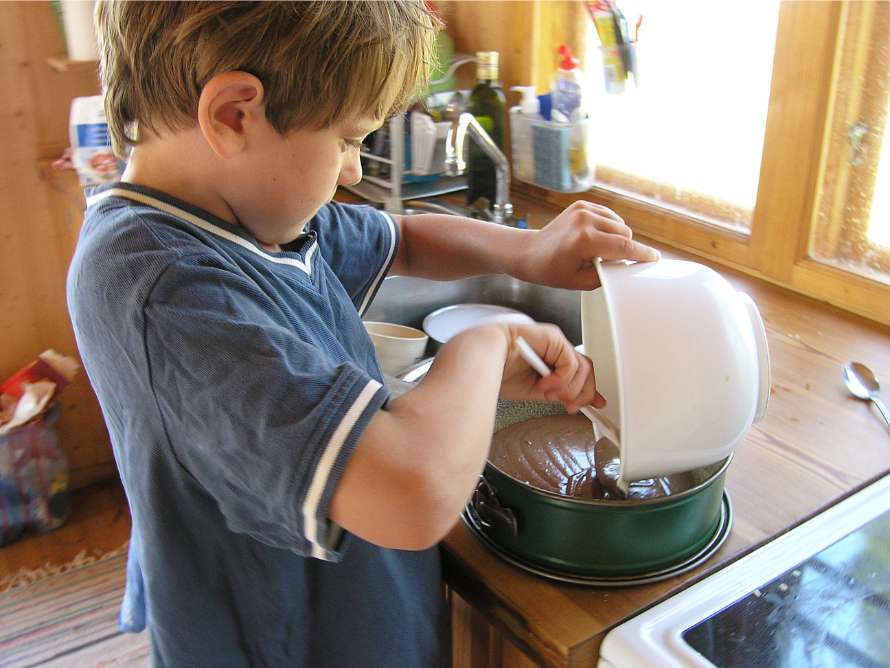 Pojken bakar en kaka i köket.