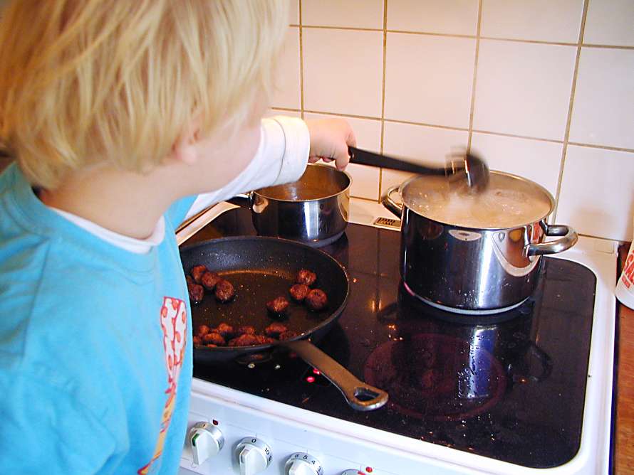 Barnet hjälper mamma att laga mat.