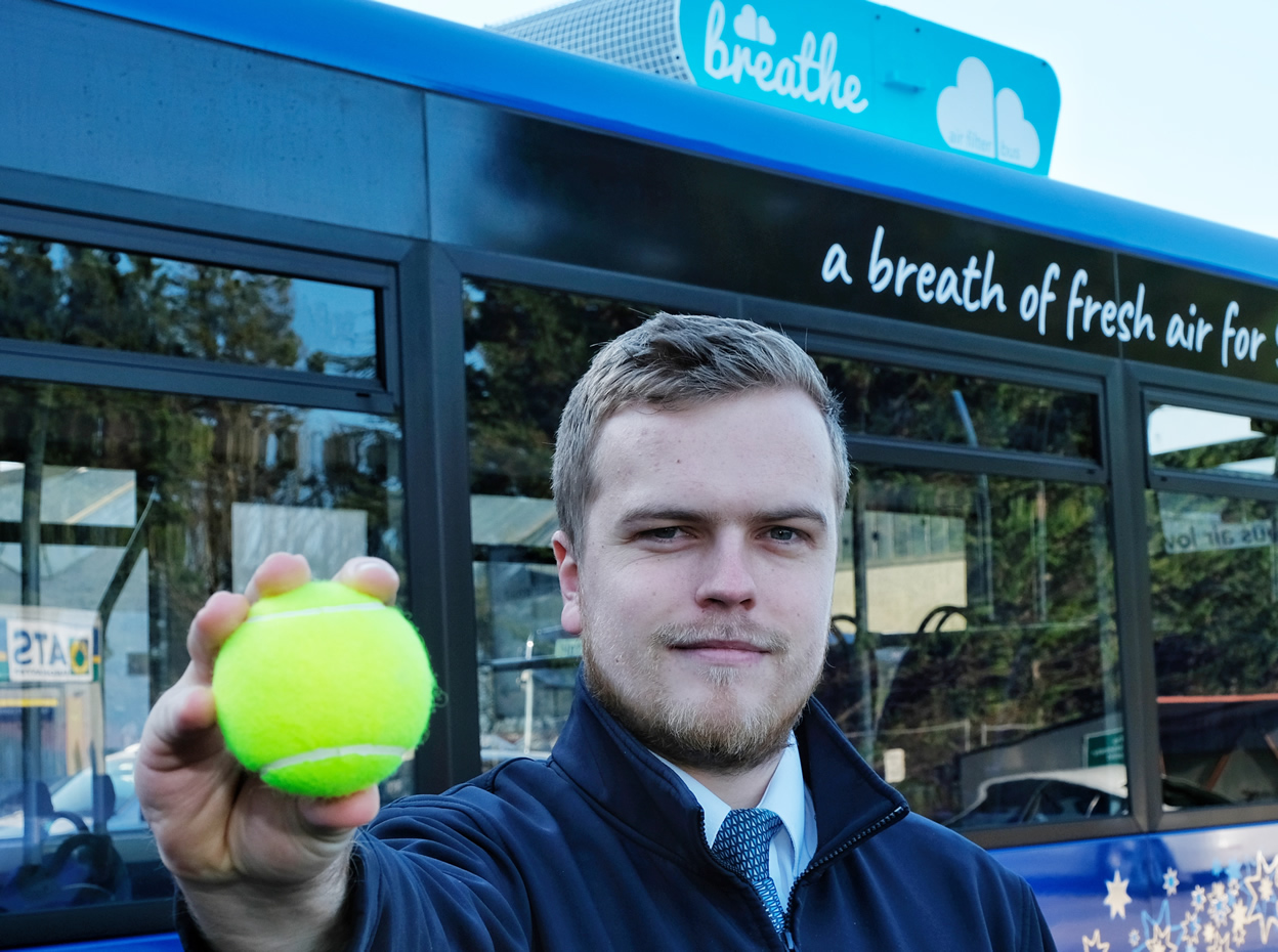 Driver holding a tennis ball - tests have shown that a single bus could remove as much as 65g of pollutants from the air – equivalent to the weight of a tennis ball