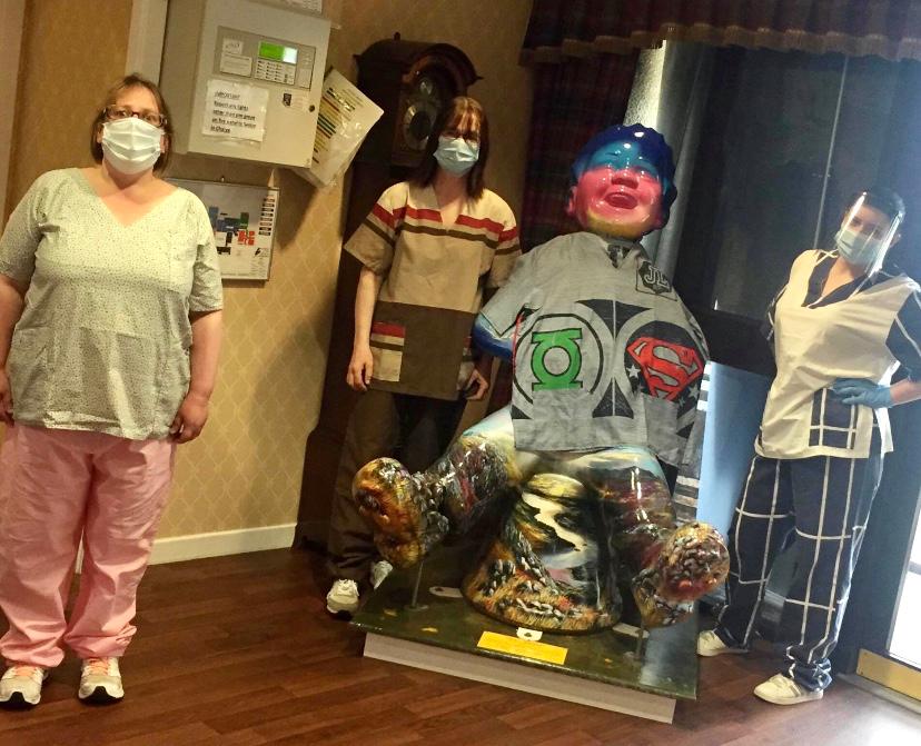 care home workers wearing new hand-made scrubs posing next to large Oor Wullie statue