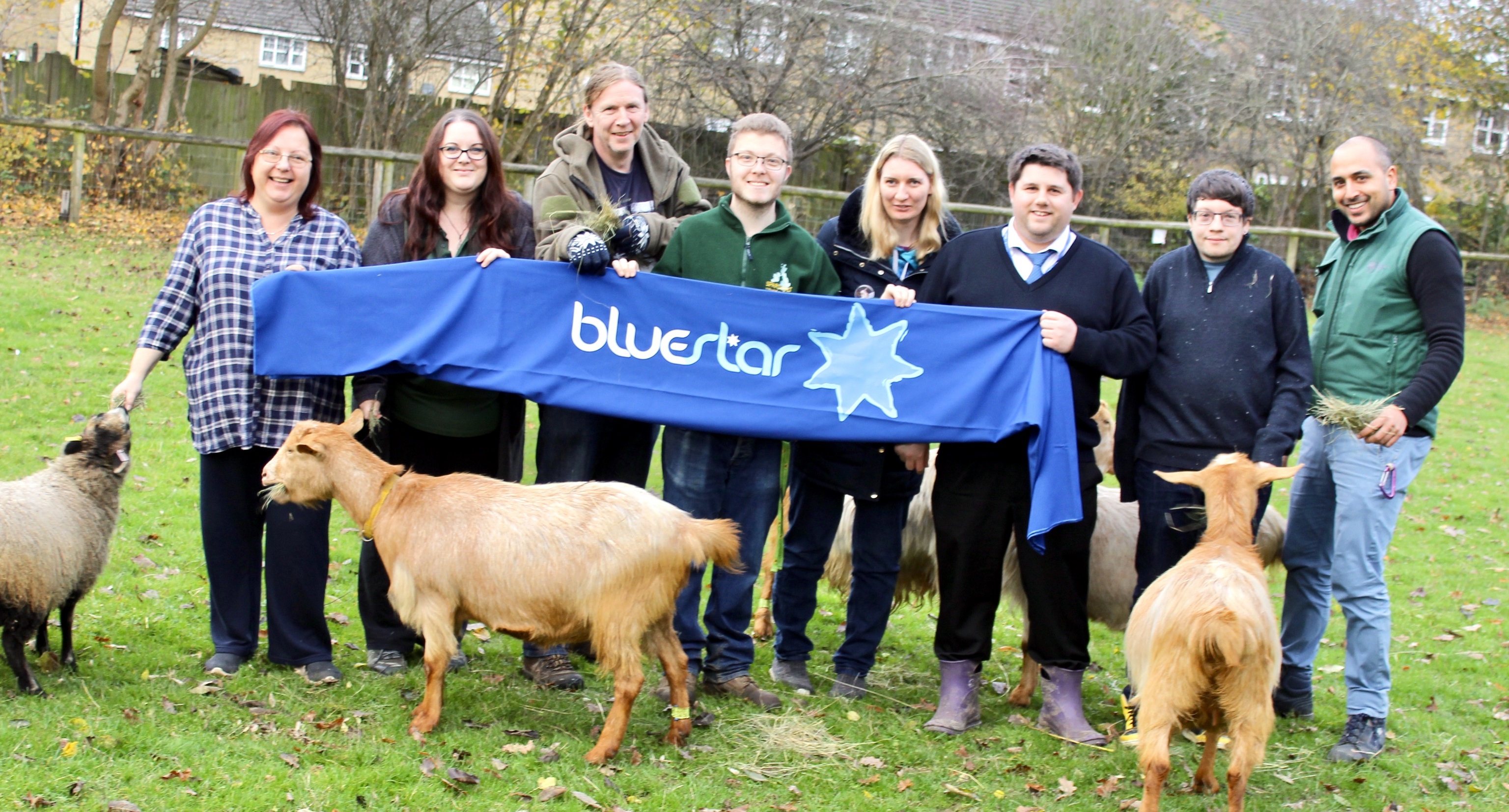 Volunteers from Southampton City Farm and Bluestar's George Miller pose surrounded by farm animals and a banner with the Bluestar logo