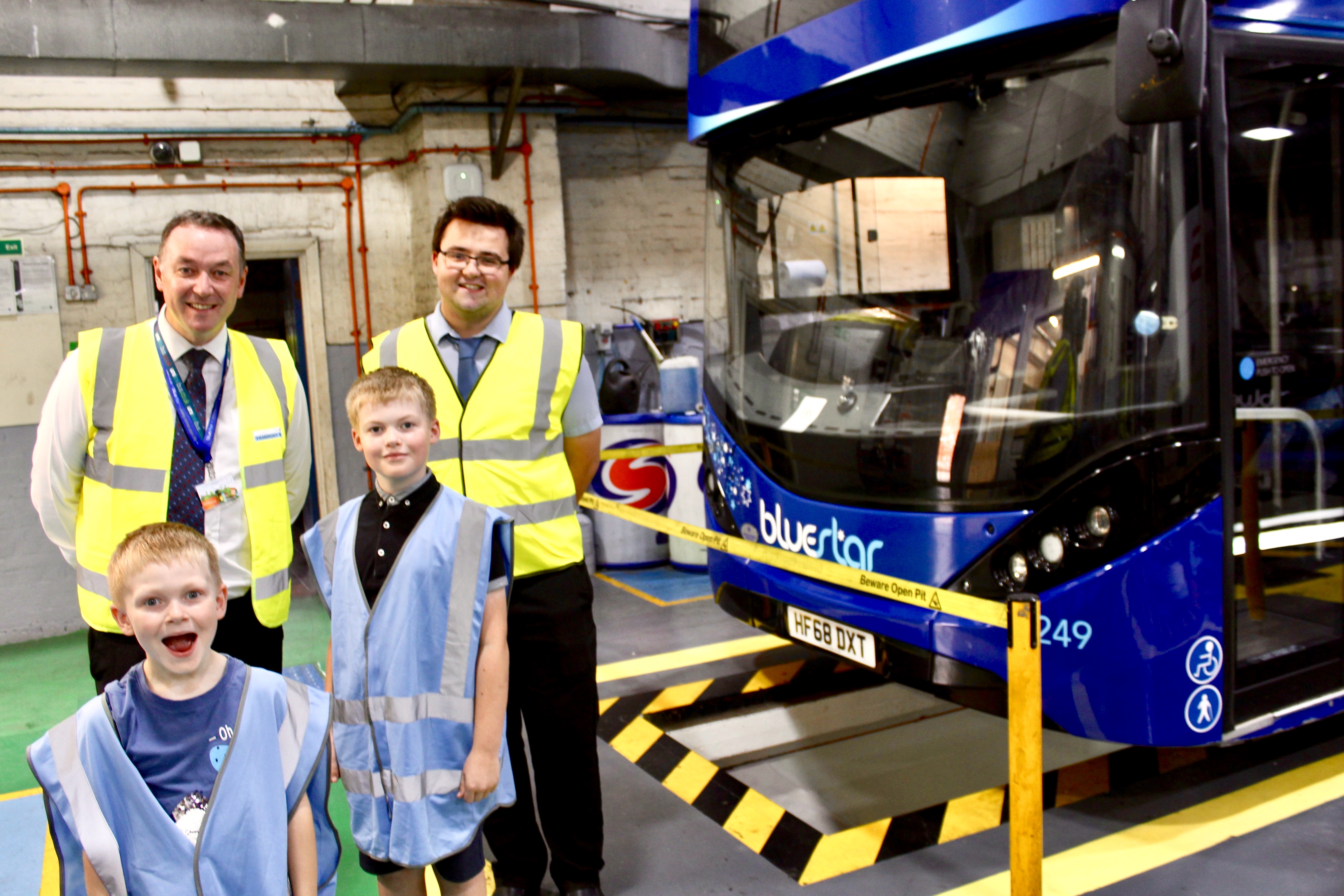Ted and his younger brother Harry with Bluestar Operations Manager Andy Shaw in front of a bus in the garage