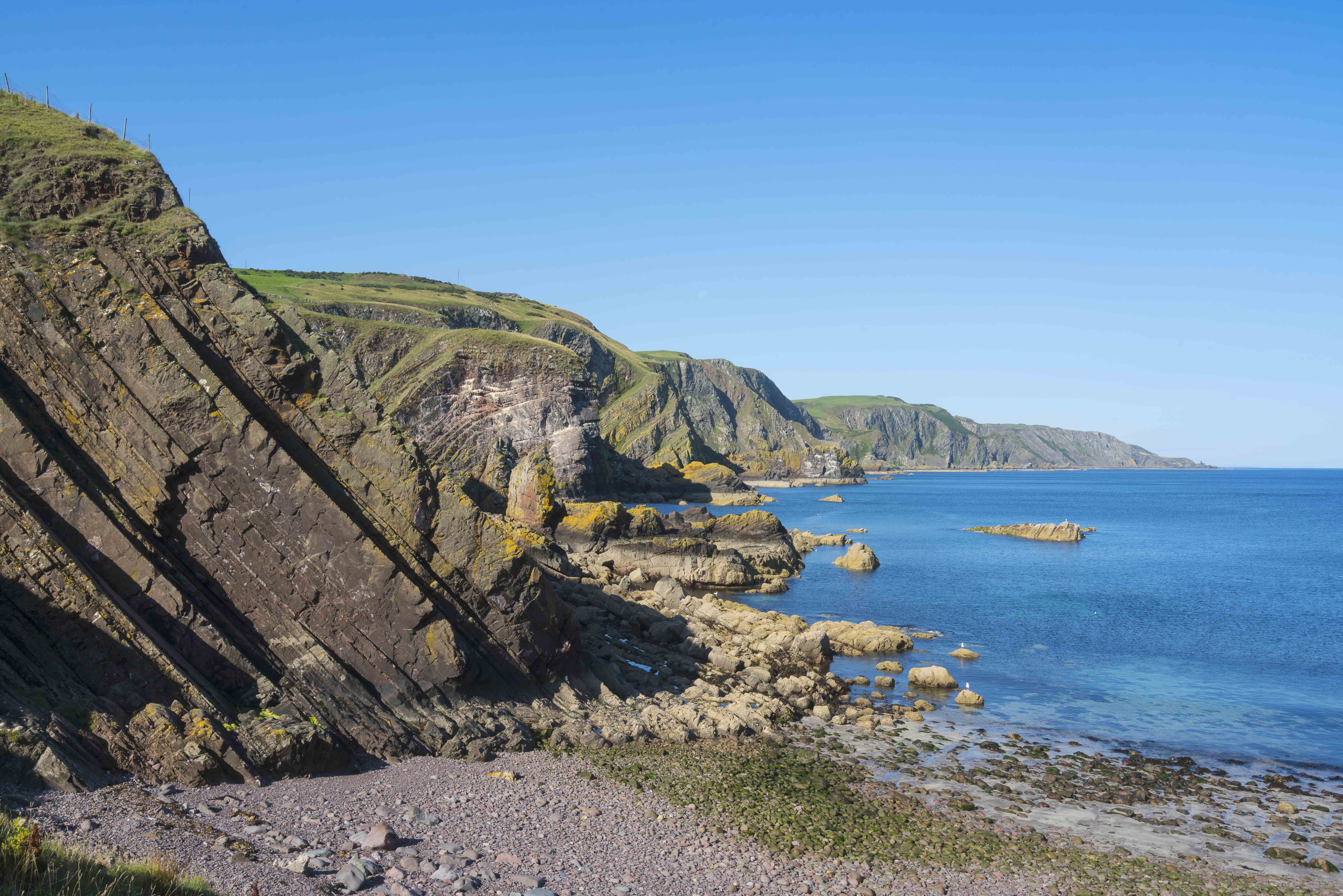 Coastal view out to blue sea with cliffs on left