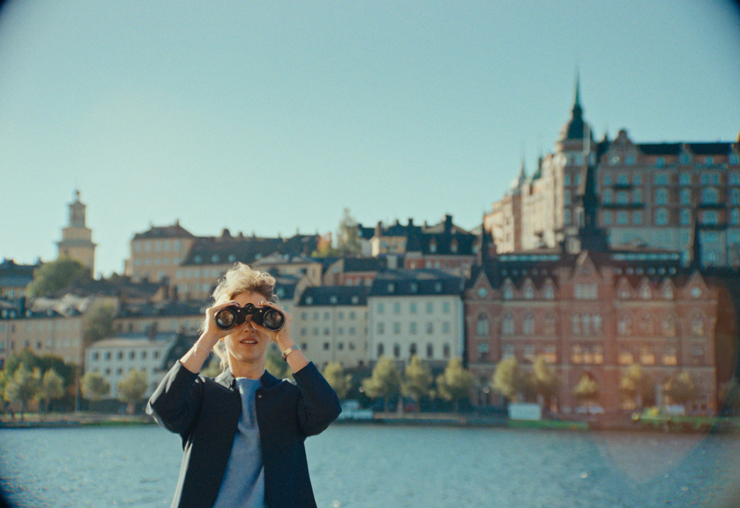 En person står med en kikare och tittar ut över Stockholms stad.