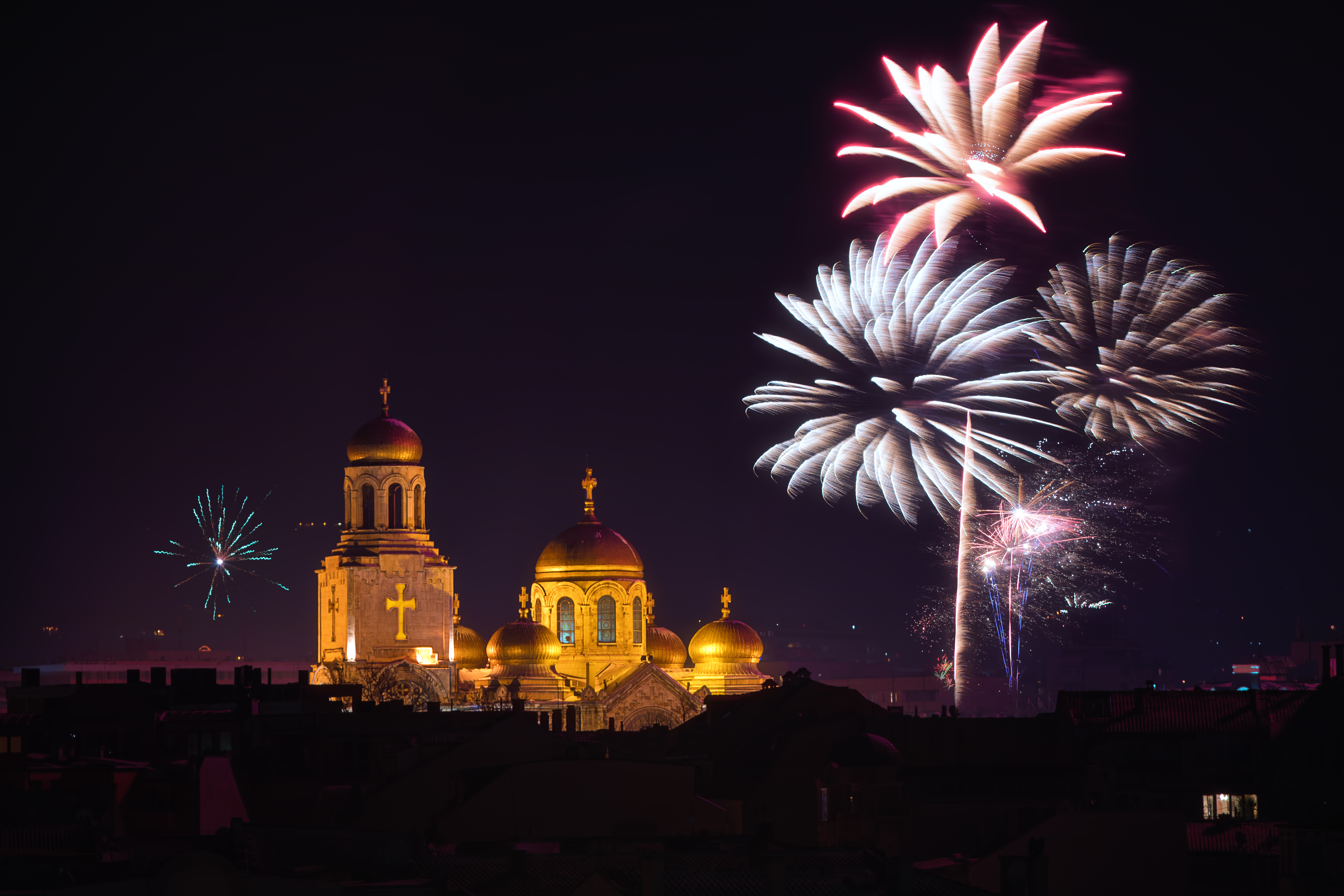 En ortodox kyrka i bakgrunden med fyrverkerier runt om på en mörk himmel.
