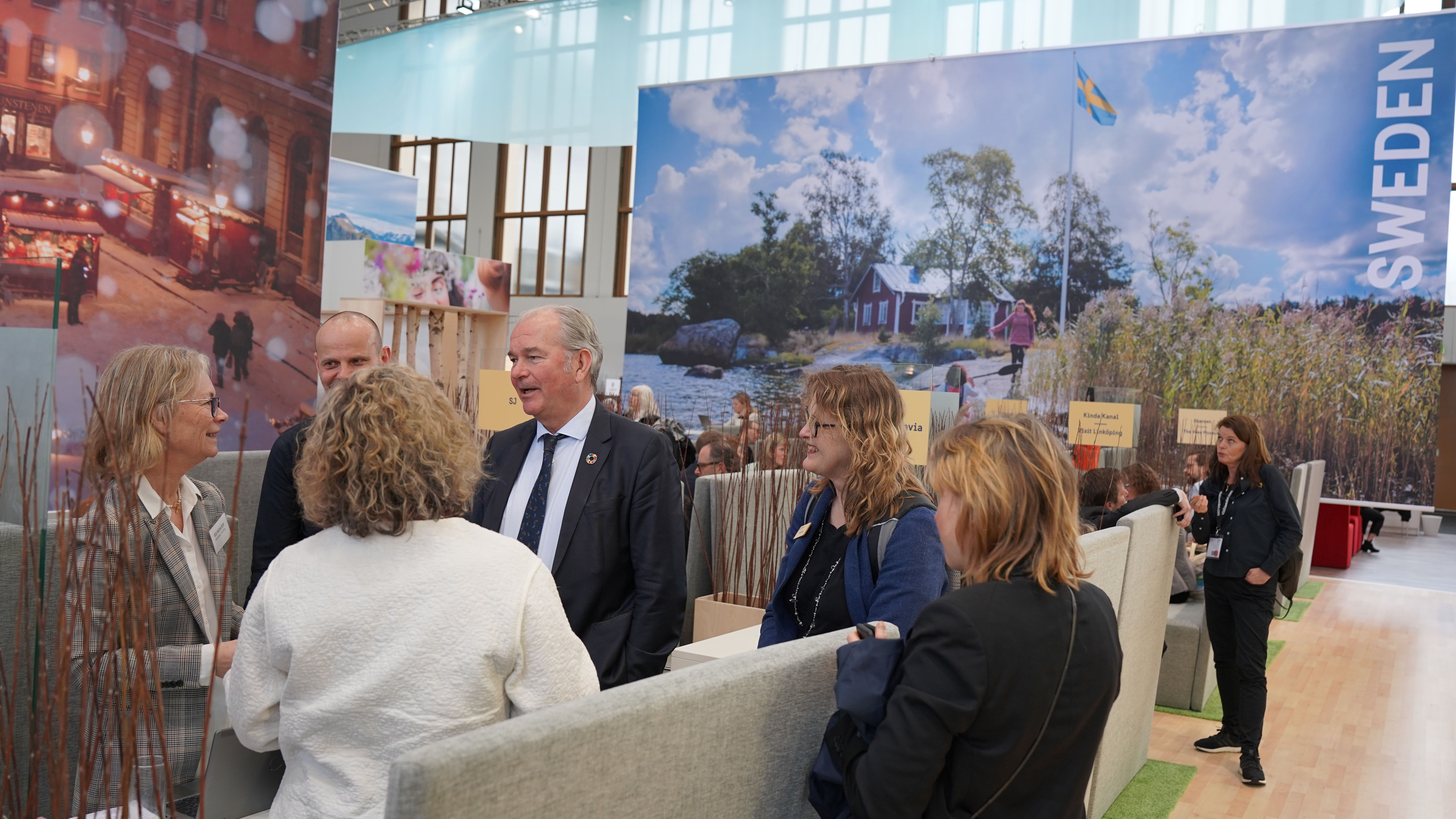 Sex personer står och diskuterar i Visit Swedens monter på ITB mässan i Berlin 2023.