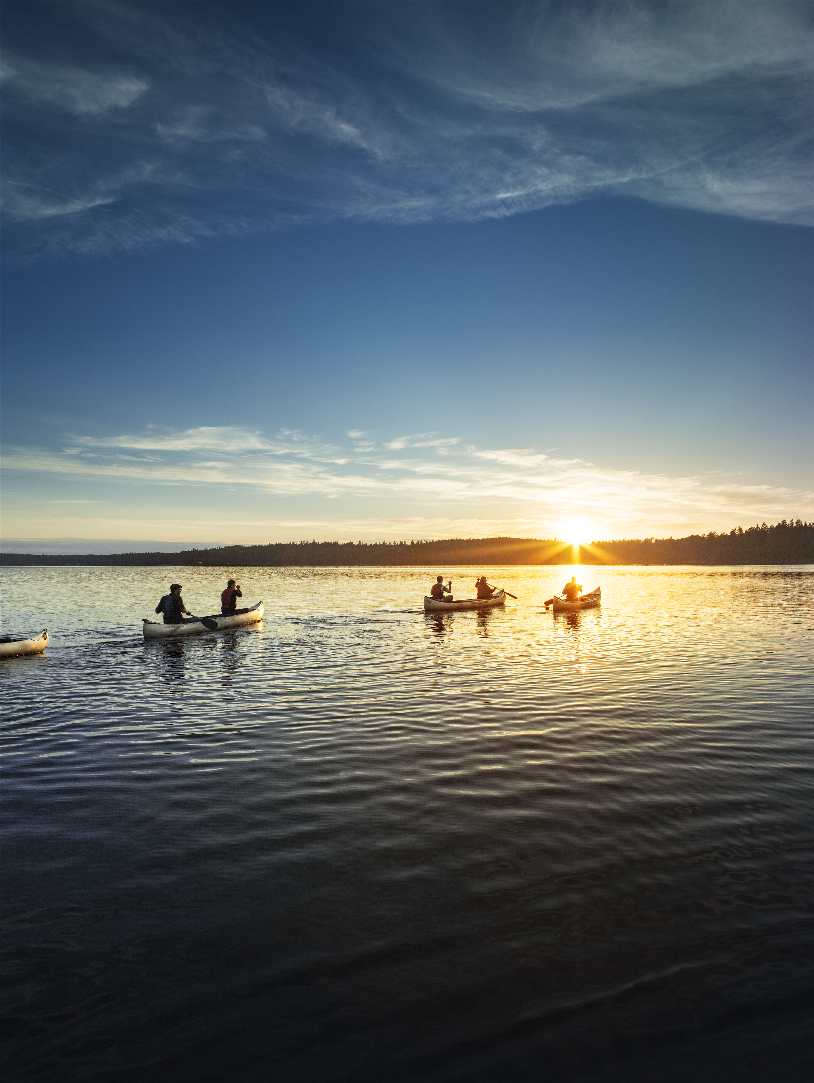 Ett par personer paddlar kajak i solnedgången.