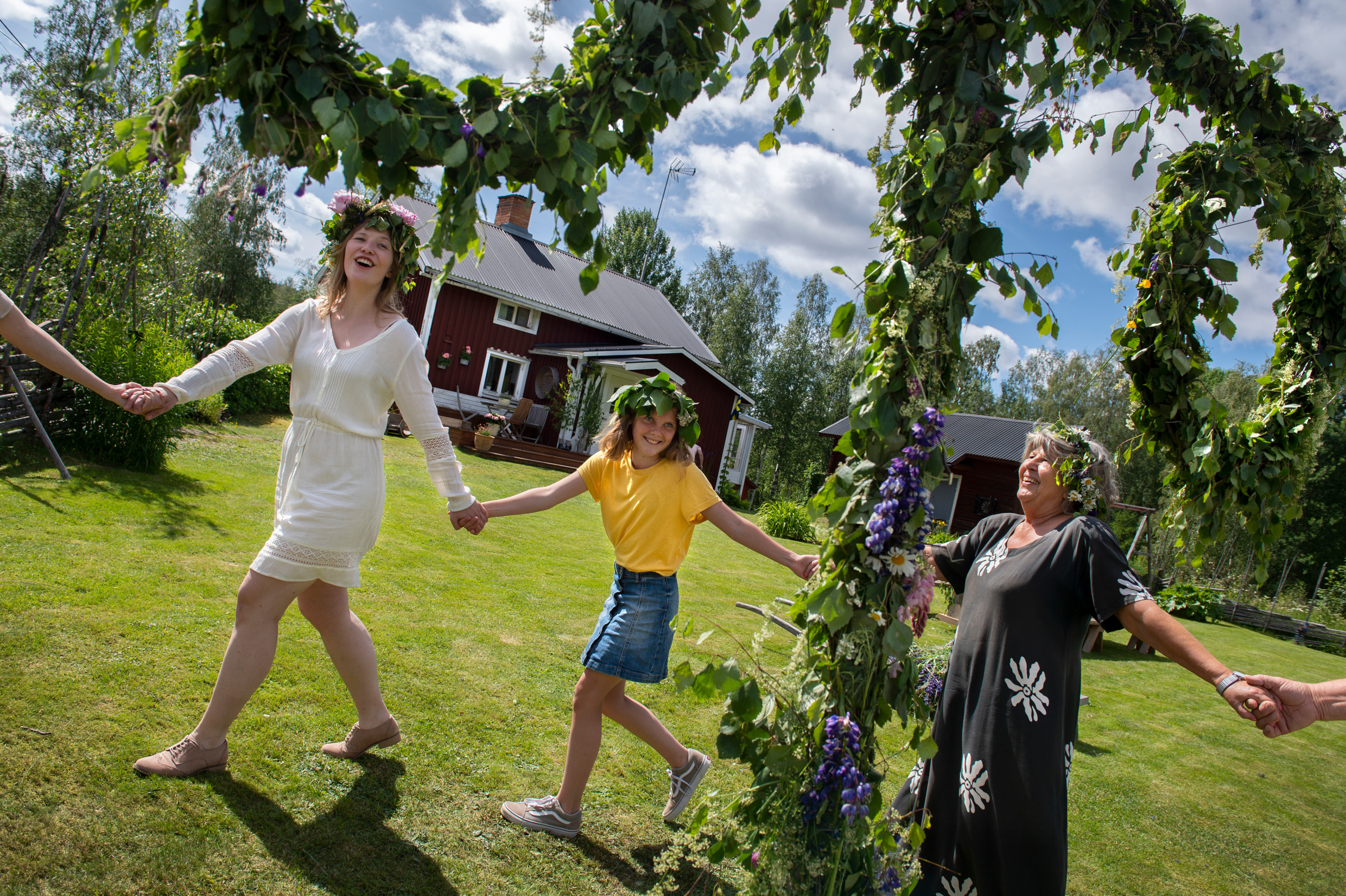 Flera personer dansar runt en midsommarstång.