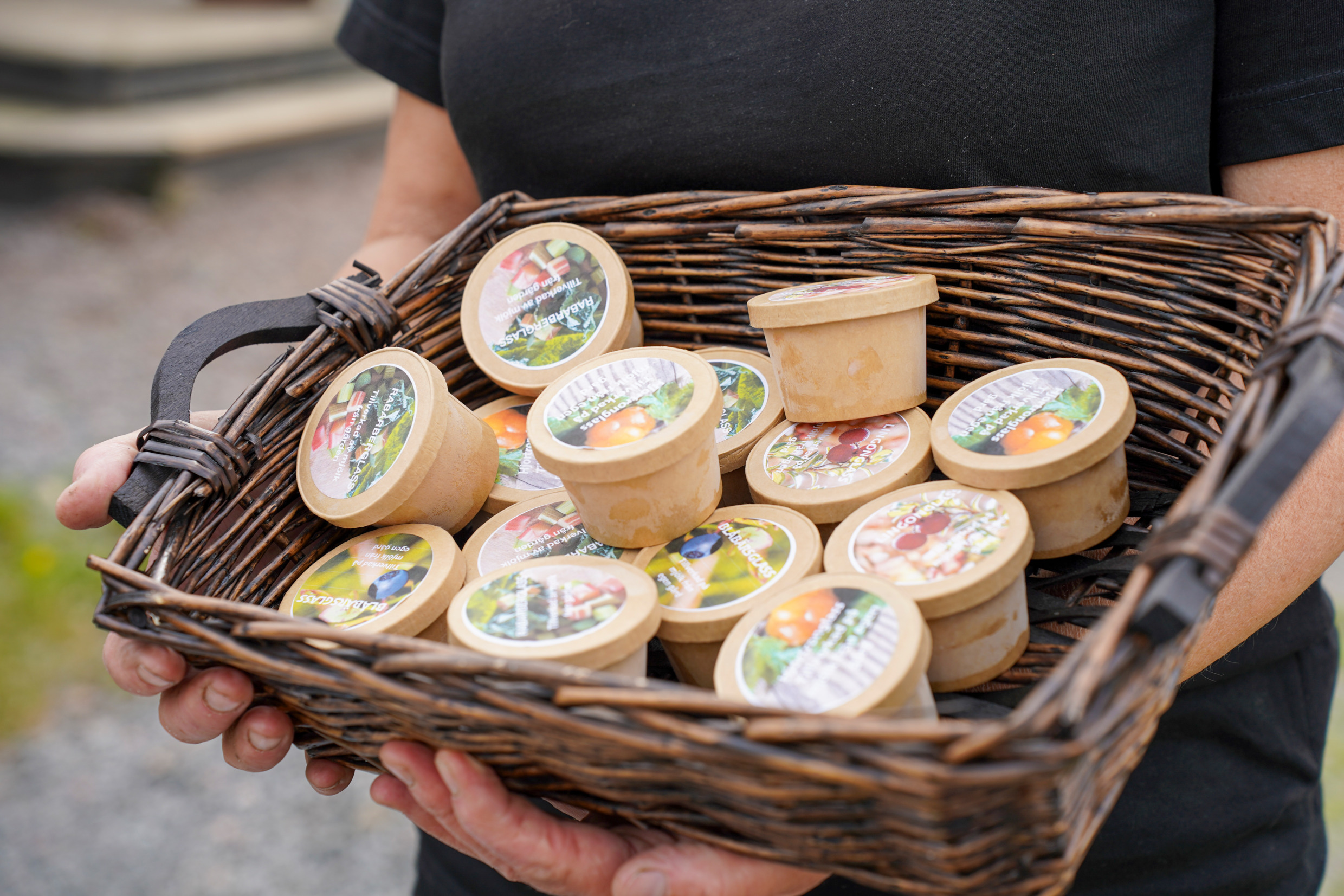 En person håller en hel korg fylld med små förpackningar med lokalproducerad glass.