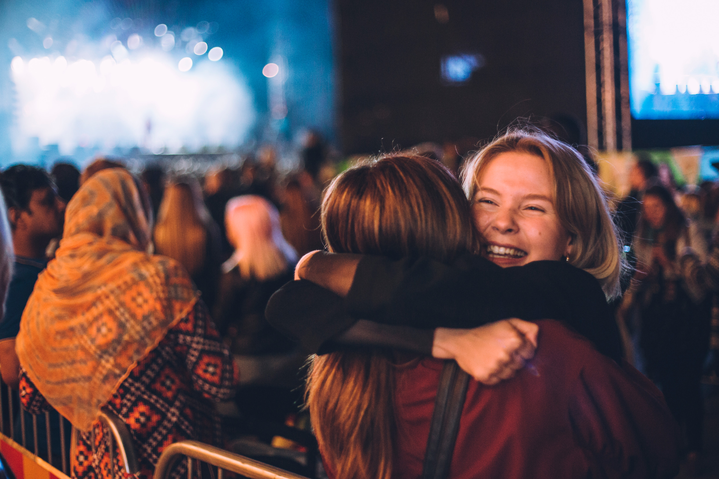 Två tjejer kramar om varandra på en utoomhuskonsert.