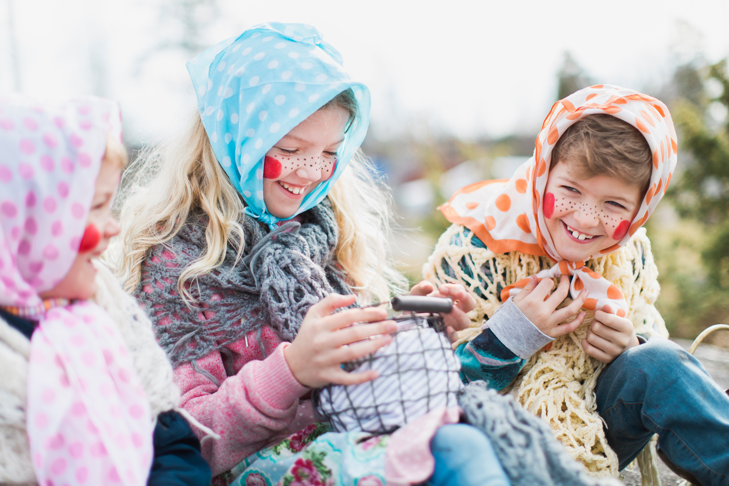 Tre små påskkärringar sitter och fnissar med varandra på en bänk.