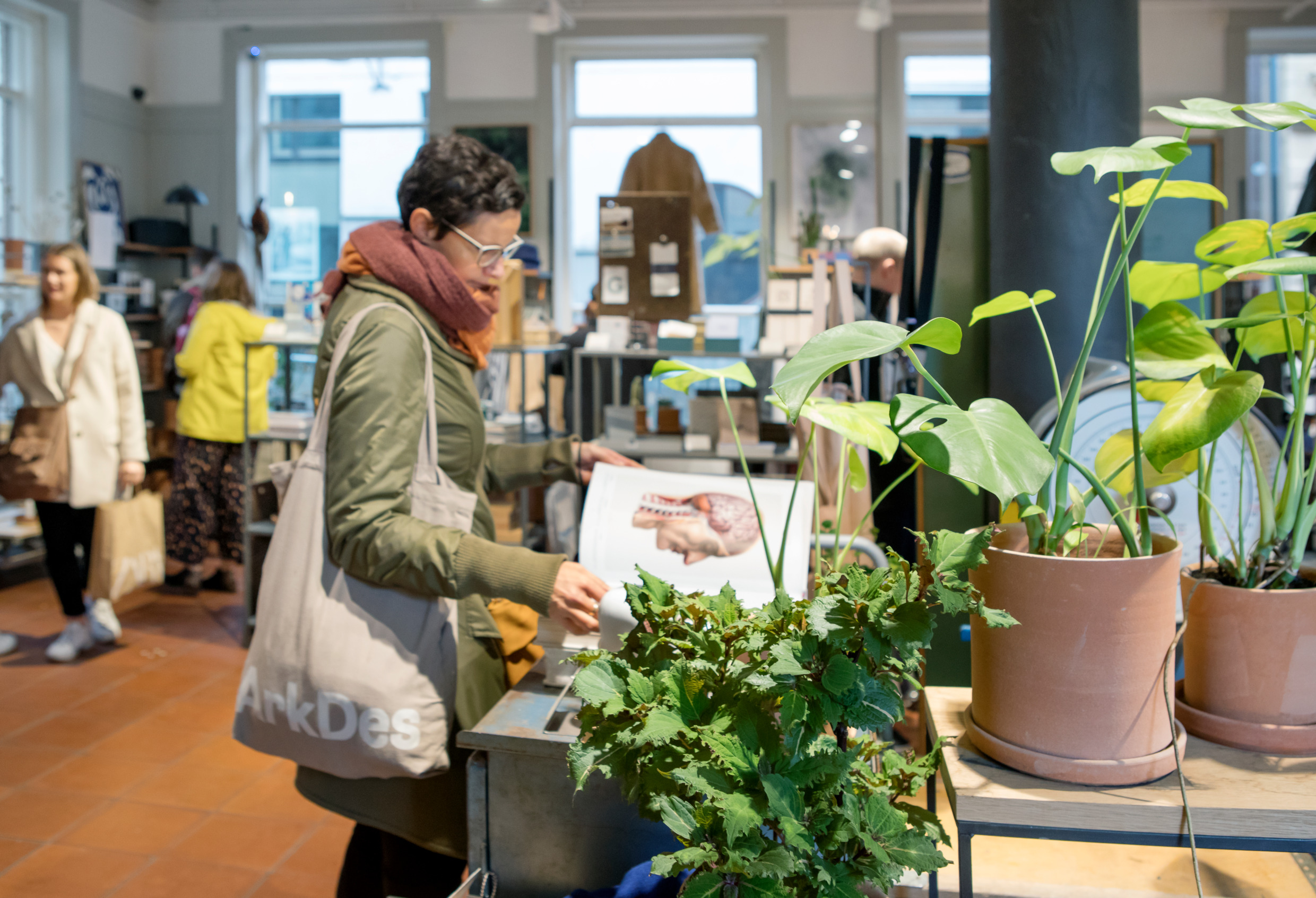 En kvinna bläddrar i en bok med bilder i en affär full med designsaker.