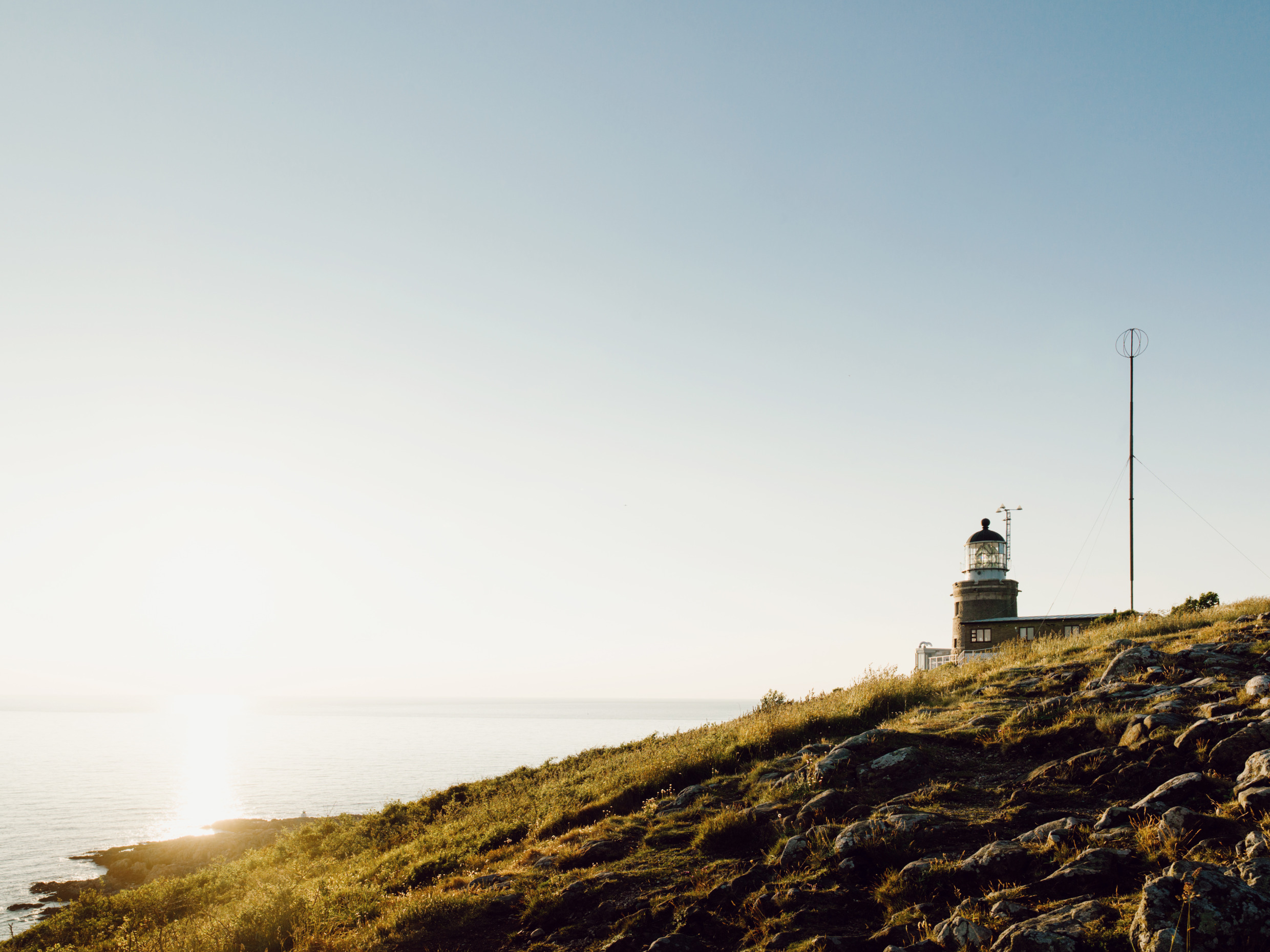 En fyr på en kulle framför havet.