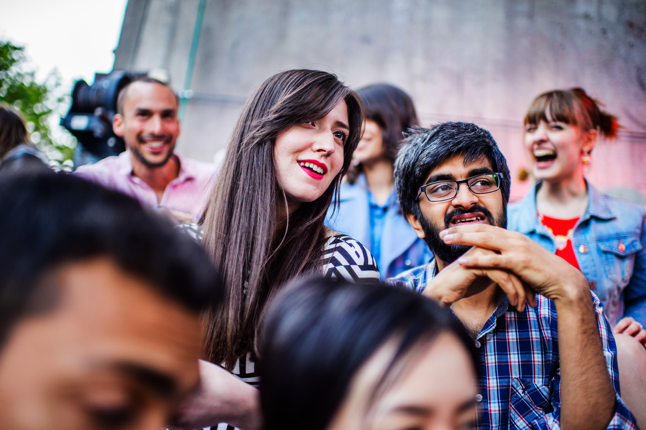 Ett gäng personer sitter ner, två personer i mitten sitter och tittar på något längre bort. De i bakgrunden ser glada ut.