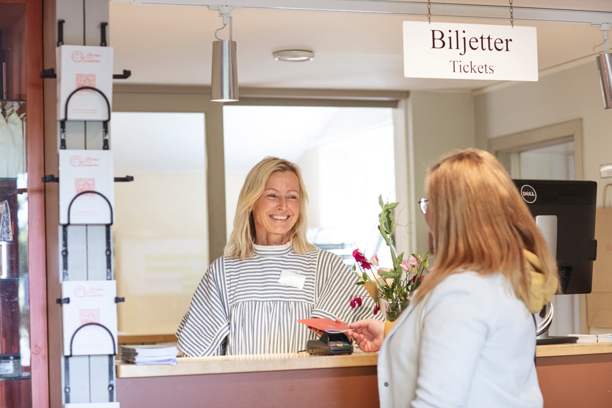 En kvinna köper en biljett över disk till Carl-Larsson museet.