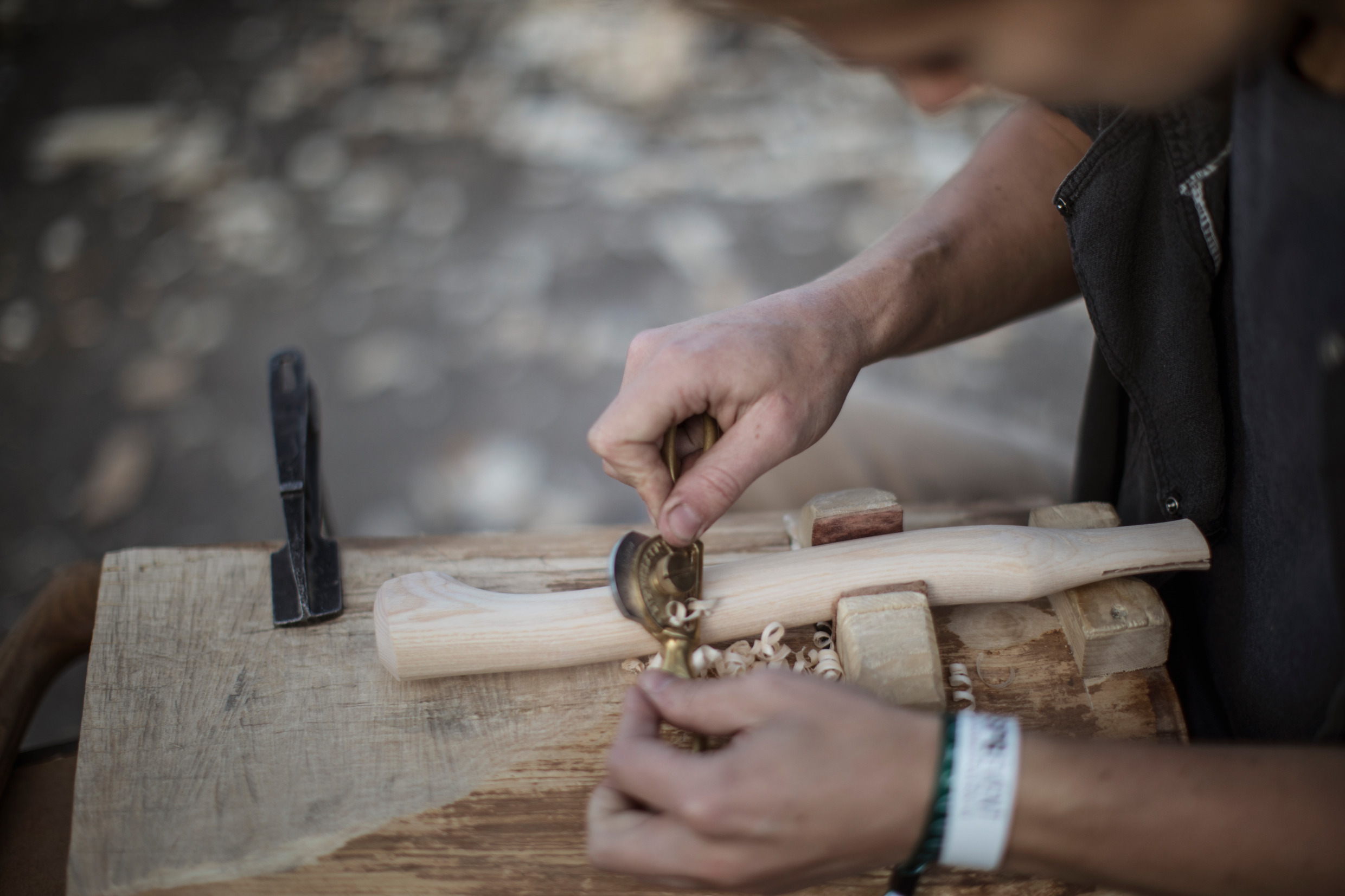 En man sitter och tillverkar handtaget till en yxa.