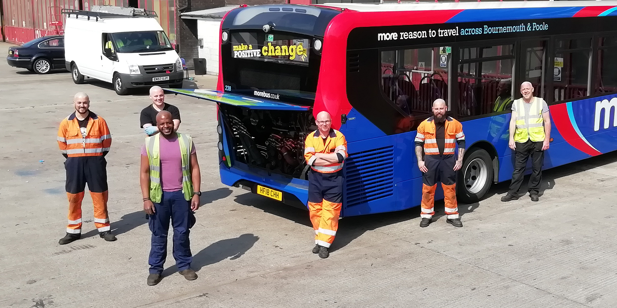 Photo of morebus engineers with shaved heads next to a morebus bus