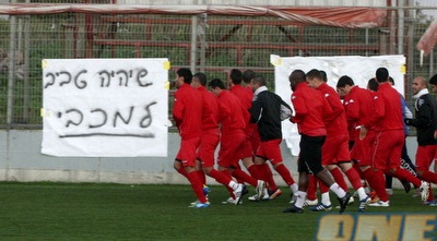 שחקני הפועל תל-אביב על רקע השלטים (דרור רוזנפלד)