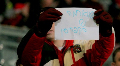 אוהד הפועל עם שלט המכוון לבן שמעון (משה חרמון)