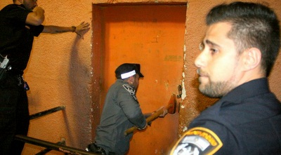 שוטר פורץ את השער עם גרזן (משה חרמון)
