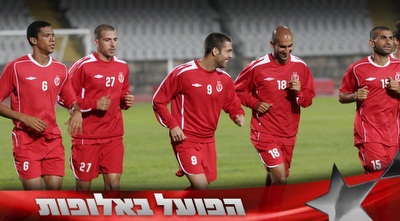 שחקני הפועל מתחממים. בקבוצה בטוחים ביכולת לנצח את בנפיקה (רועי גלדסטון)