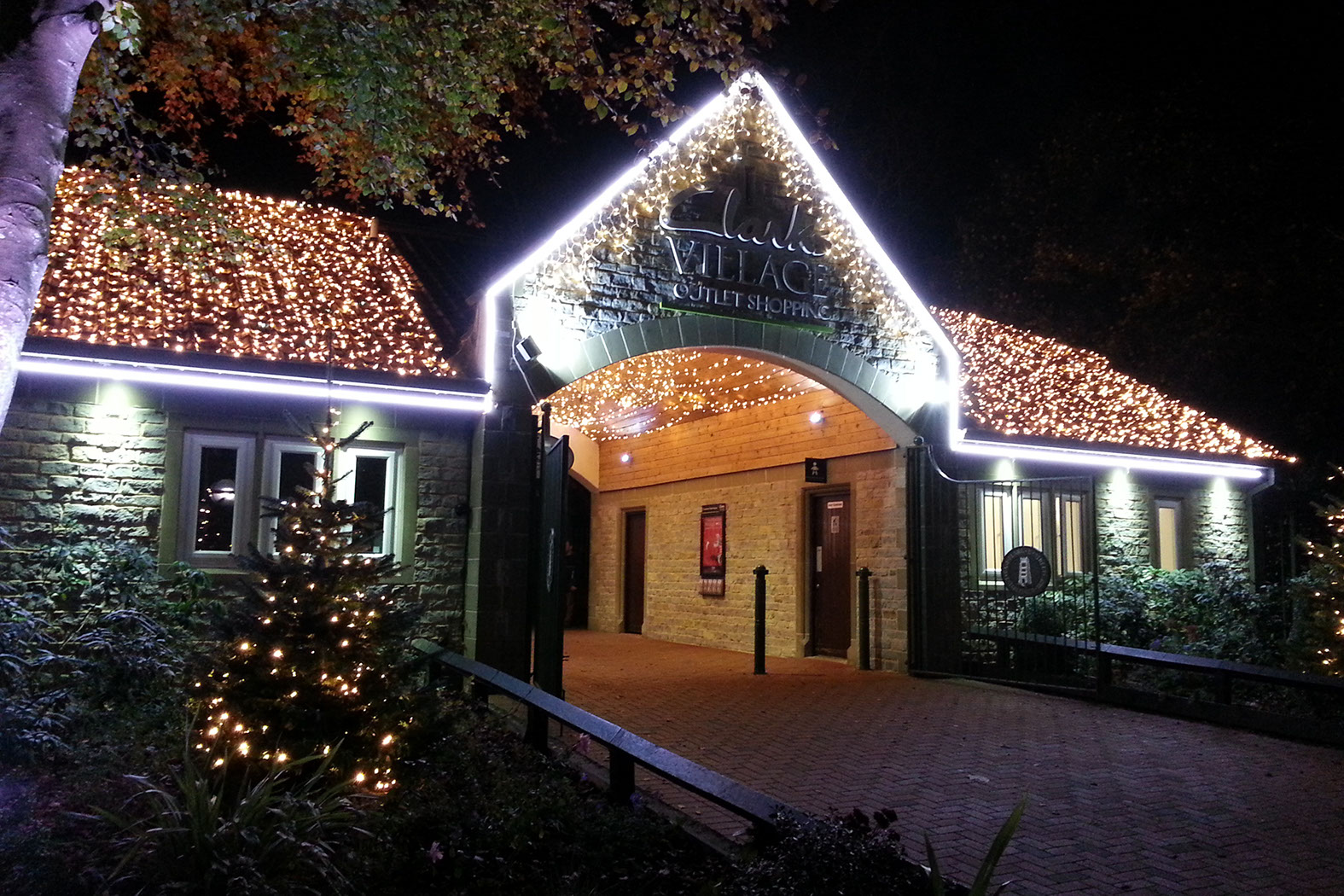 Entrance building with roof covered in light strings and warm white icicle lights on the eaves