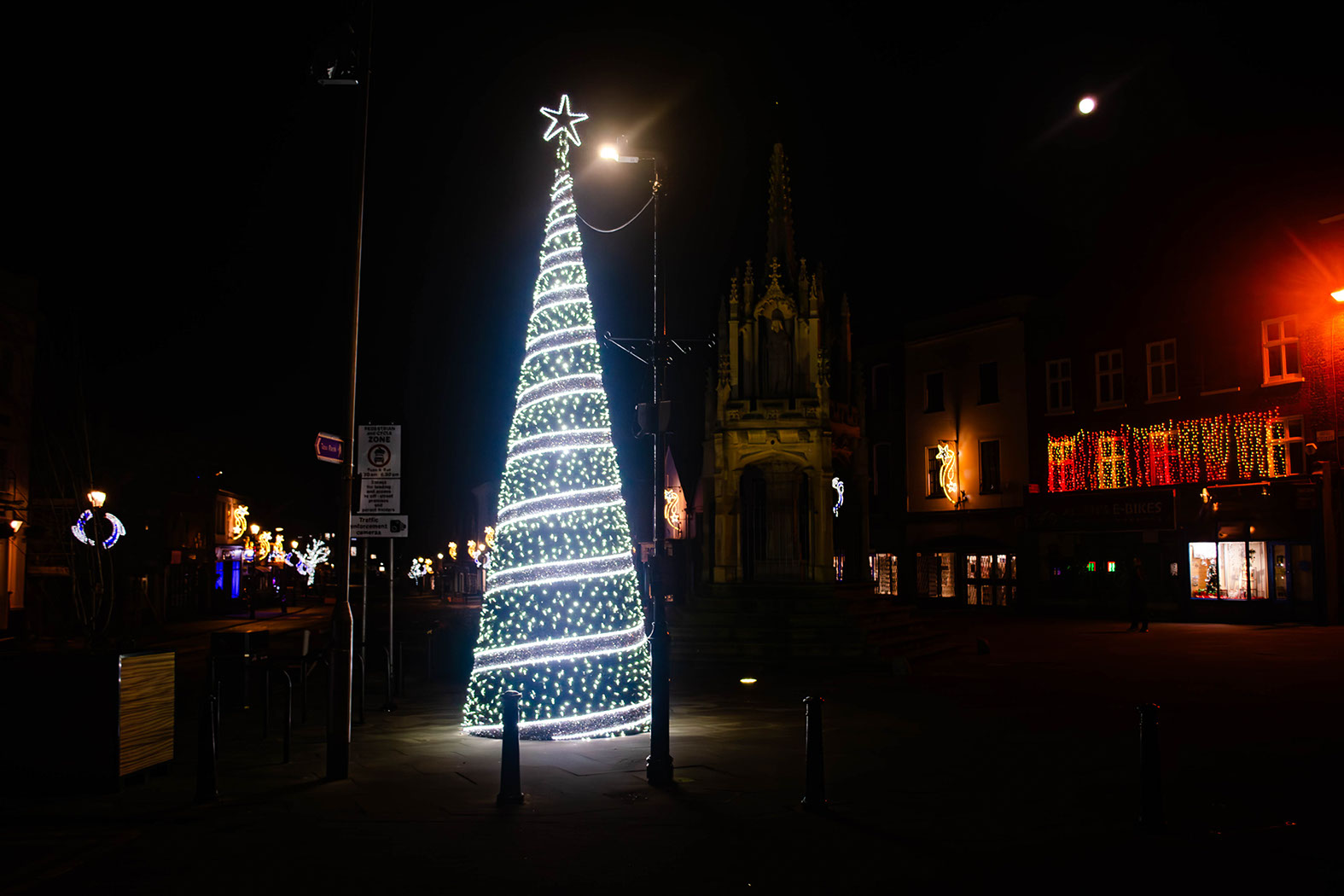 Christmas cone tree decorated with spiraled silver ribbon, white lights, and a star